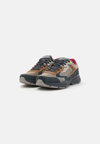 Des chaussures avec un design en matériaux mélangés dans des teintes de marron, gris et marine, avec une surface texturée et un dessus en maille à motifs.