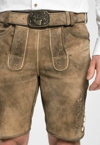 Lederhosen en daim marron avec une broderie florale complexe, une boucle décorative et des accents de boutons sur les côtés. Texture unique et coupe ajustée.