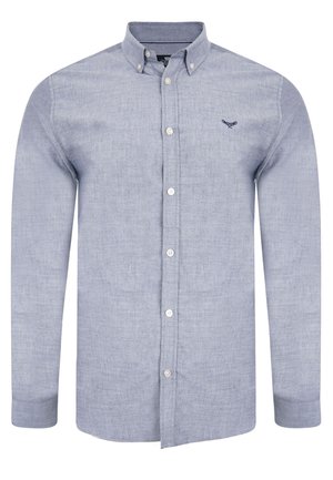 Lyseblå skjorte med knaplukning lavet af bomuld. Har en krave, standard knapper og et broderet logo på venstre bryst. Lange ærmer.