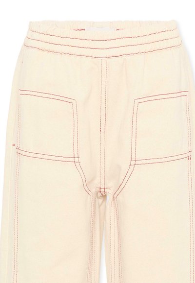 Pantalon beige avec ceinture élastique et surpiqûres rouges proéminentes soulignant les poches avant et les coutures.