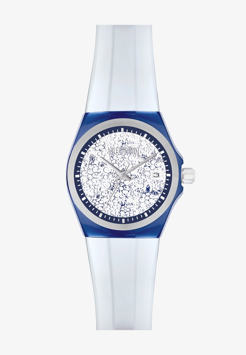 Modré a čiré silikonové hodinky s kruhovým bílým ciferníkem, který má texturované modré vzory, stříbrné hodinové značky a datumový ukazatel na pozici tři.