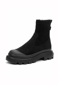 Bottines noires en suede avec embout en caoutchouc et semelle épaisse. Elles disposent d'un panneau latéral élastique et d'une languette à l'arrière pour un enfilage facile.