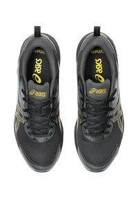 Zapatillas deportivas negras con parte superior de malla texturizada, acentos amarillos y una suela negra resistente. Cuentan con cordones y un tirador en el talón.