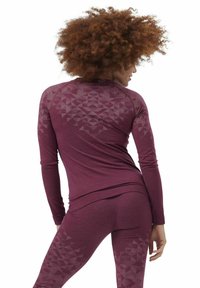 Long-sleeve burgundy activewear top with geometric pattern detail on back, paired with matching fitted leggings featuring similar accents.