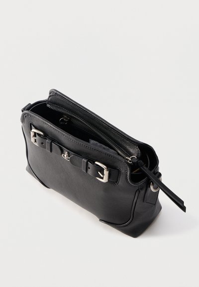 Μαύρη δερμάτινη τσάντα χειρός με δύο ασημένιες αγκράφες στο μπροστινό μέρος, κυρίως διαμέρισμα χωρίς φερμουάρ και μακριά τσέρκι φερμουάρ σε απλό φόντο.