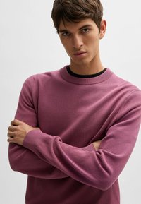 Kaulusneule teksturoidussa purppurakuidussa. Varustettu ribbaustuilla hihansuilla ja helmalla, slim fit -mallilla ja rennolla muotoilulla. Kangas näyttää pehmeältä ja hengittävältä.