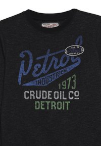 Black cotton t-shirt with crew neck. Features blue and green text: "Petrol Industries 1973 Crude Oil Co Detroit" and a circular logo.