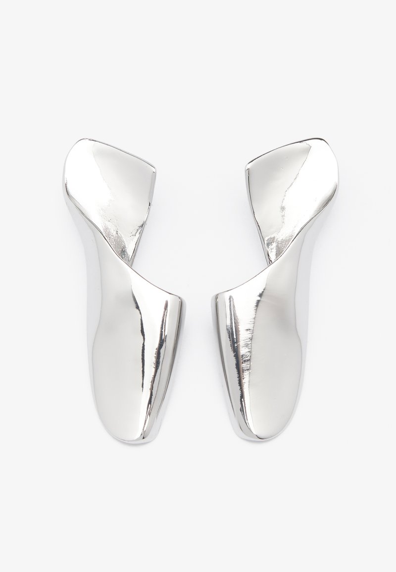 Sølvåpne sko med en elegant, buet design. Glanset finish, glatt tekstur og unik asymmetrisk form. Ingen synlig metall eller detaljer.