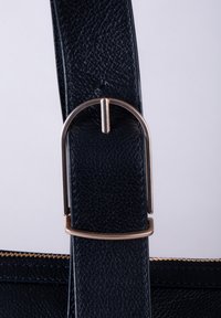 Black textured leather bag strap with a metallic gold-colored buckle and stitching, featuring a smooth interior lining and a zipper closure.