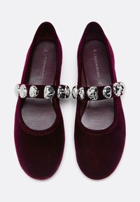 Burgundske baršunaste Mary Jane čevlje z zaokroženim nosom in dekorativnim srebrnim zaponko čez nart. Mehka teksturirana notranjost.