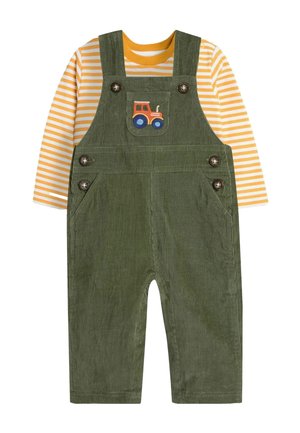 Grüne Samtüberalls mit gestreiftem gelb-weißen Langarmshirt. Mit einem gestickten Traktor-Patch und Knopfakzenten an den Trägern.
