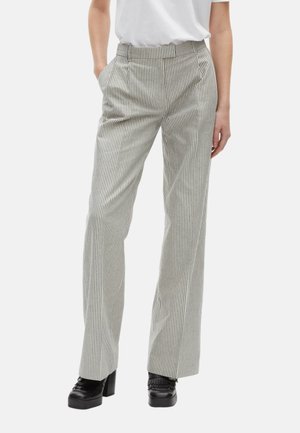 Pantaloni a vita alta a righe grigie e bianche, con pieghe, tasche laterali e taglio dritto, abbinati a scarpe platfotm nere.