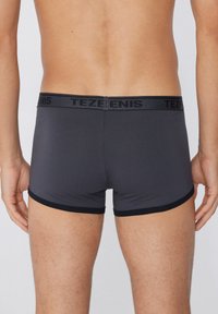 Boxers grises con una cinturilla elástica negra que presenta la marca "TEZENIS", ofreciendo un ajuste ceñido y una textura suave.