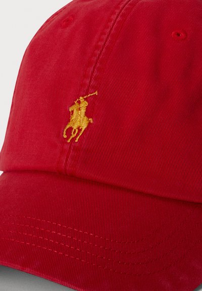 Piros baseball sapka sárga hímzett pólójátékos logóval az első panelen és látható varrással a karimán.