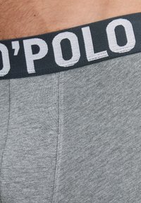 Grijze boxershorts met een zachte stofstructuur, voorzien van een donkere tailleband waarop de merknaam in witte letters is gedrukt.