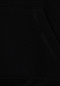 Veste à capuche noire en matériau texturé, avec une poche frontale et des coutures visibles le long des bords. Tissu doux et extensible.