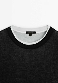 Black T-shirt with a textured finish, featuring a round neckline with contrasting white trim and a label on the inside collar.