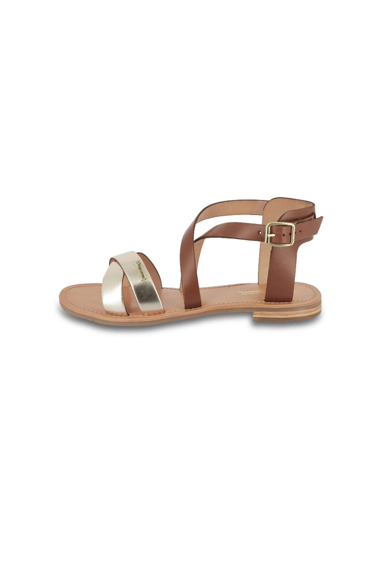 Brown leather sandal with metallic silver cross strap, adjustable ankle buckle, flat sole, and minimalistic design. Suitable for casual wear.