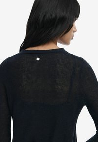 Navy knit sweater featuring a textured pattern, a round neckline, and a silver hardware accent at the back. Light and slightly sheer fabric.