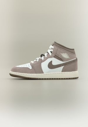 Baskets Air Jordan 1 montantes mi-hautes en daim blanc et marron clair avec lacets blancs et swoosh Nike sur le côté.
