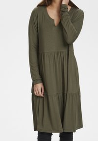 Długa zielona sukienka z długim rękawem i dekoltem w kształcie litery V, z warstwowym wzorem spódnicy oraz miękkim, teksturowanym materiałem.