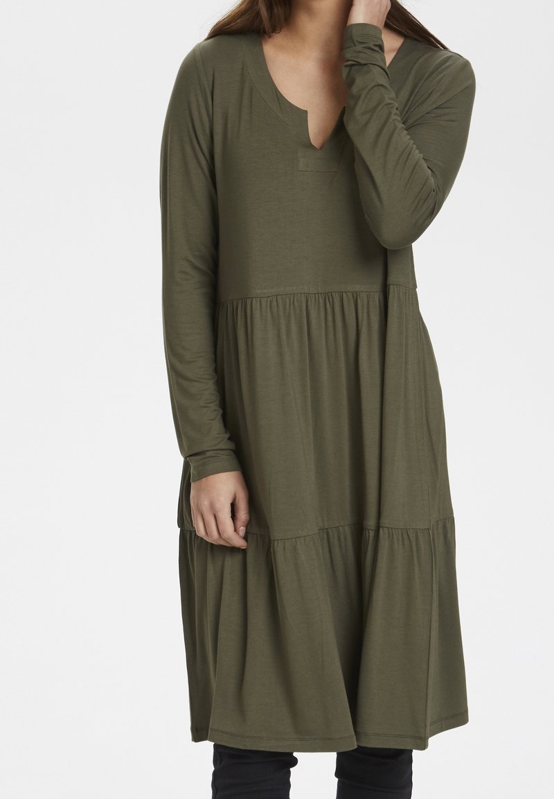 Długa zielona sukienka z długim rękawem i dekoltem w kształcie litery V, z warstwowym wzorem spódnicy oraz miękkim, teksturowanym materiałem.