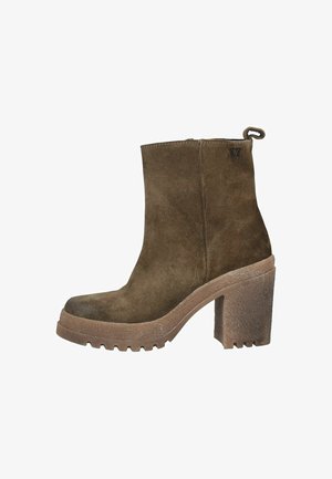 Bottillon en suede marron avec un talon épais, semelle en caoutchouc texturé, fermeture zippée et une lanière au dos. Présente un discret détail de logo.