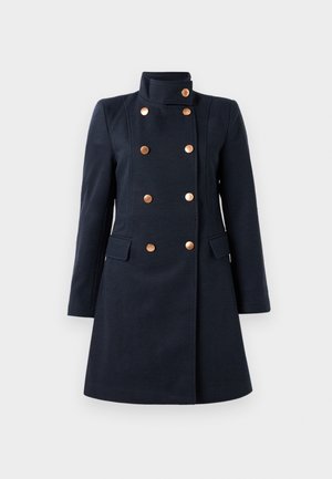Manteau bleu marine à double boutonnage avec un col haut, huit boutons en laiton, manches longues et deux poches à rabat à l'avant, coupe ajustée.