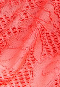 Koral textured tyg med intrikata blommönster och geometriska mönster, med transparenta utskärningar och ett smidigt, stretchigt material.