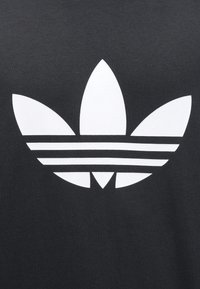 Black cotton fabric featuring a large white trefoil logo with three leaves and three horizontal stripes across the center.