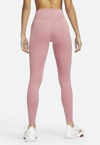 Höga, åtsittande leggings i en mjuk rosa tyg, med en slät yta och en liten vit logga ovanför höger ankel.
