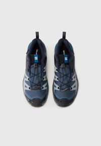 Buty sportowe z ciemnoniebieską siateczką, szarymi gumowymi akcentami, solidną podeszwą, systemem szybkiego sznurowania oraz wyprofilowanym językiem dla większego komfortu.