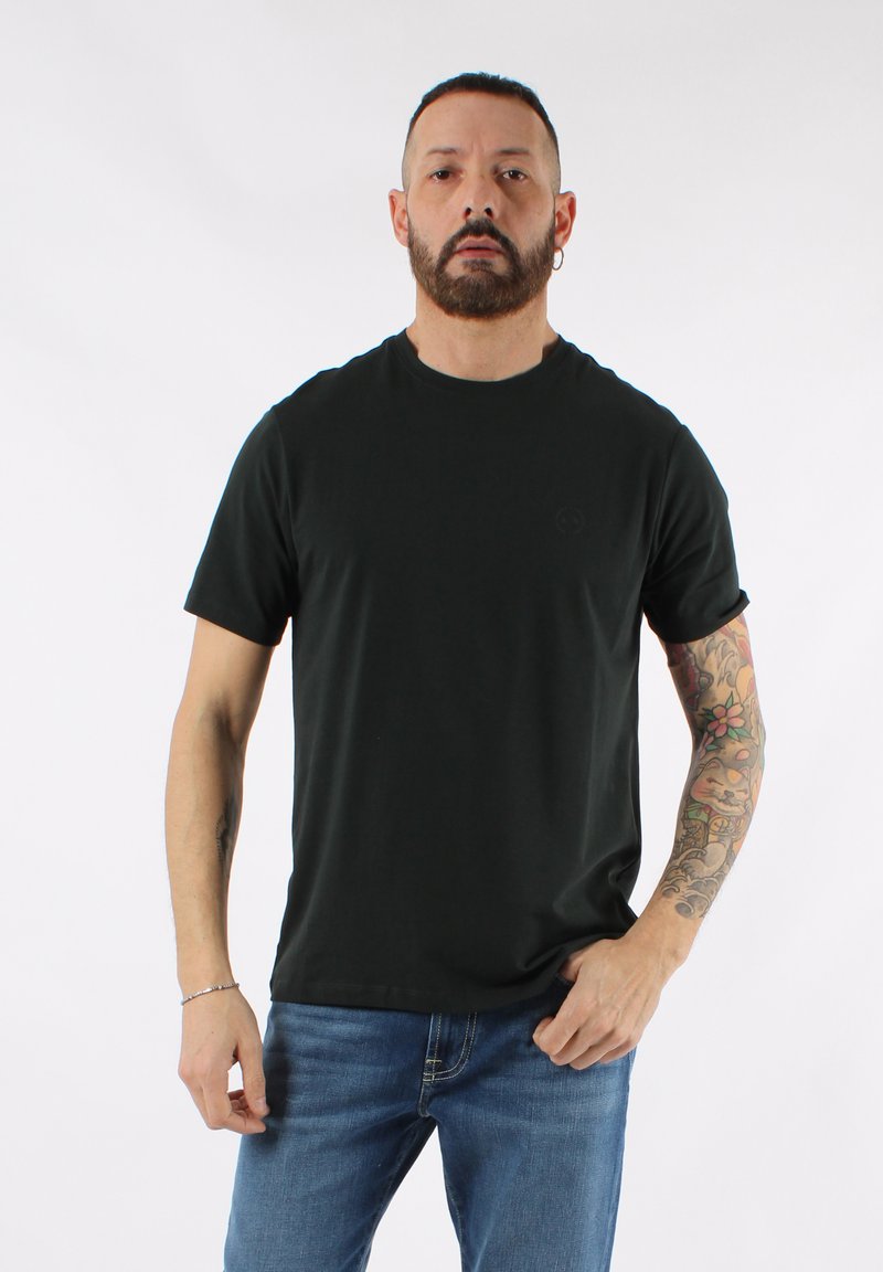 Camiseta de cuello redondo de algodón negro con mangas cortas, con un logo sutil y un ajuste estándar, combinada con jeans de mezclilla azules.