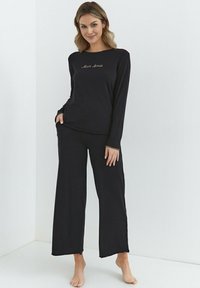 Czarny zestaw do relaksu z długim rękawem ozdobiony haftem "Mon Amie", w komplecie szerokie spodnie wykonane z miękkiego, lekkiego materiału.