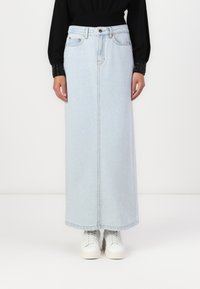 Svetlo modra denim maxi krilo s ravnim krojem, sprednjimi žepi in diskretnimi šivi, v kombinaciji z belimi supergami.