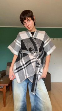 Top envolvente de padrão xadrez em preto, branco e cinza, com mangas curtas e cintura atada. Tecido suave com um corte relaxado.