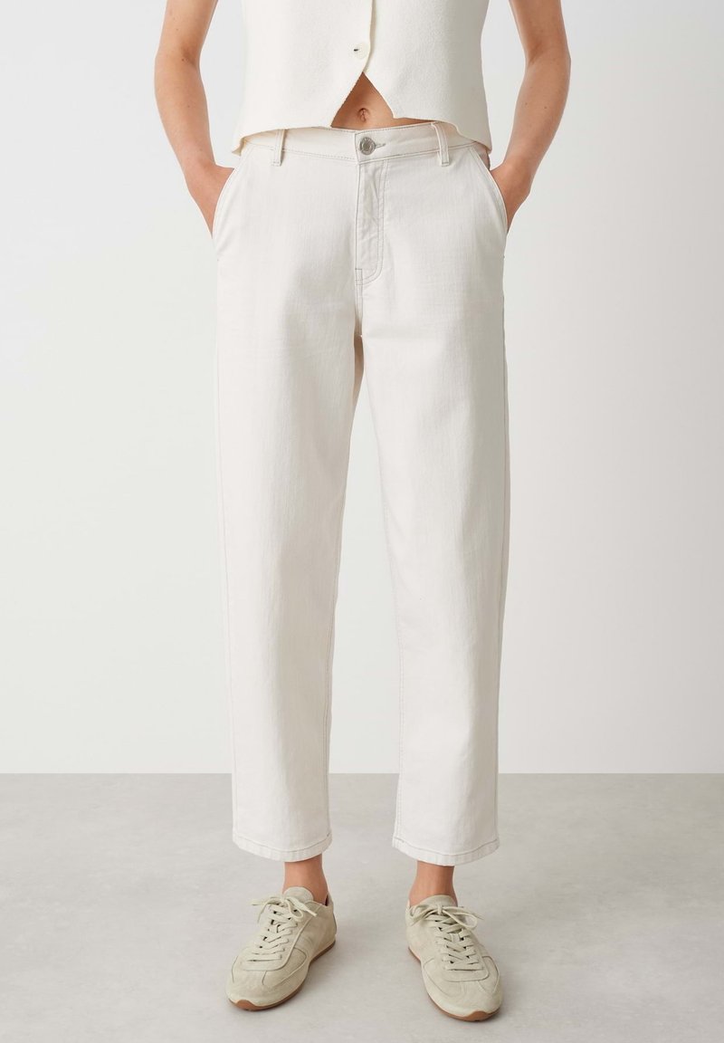 Pantalons cropped beige clair en denim, dotés d'une fermeture à bouton, de poches latérales et d'une coupe droite. Associés à des baskets grises.