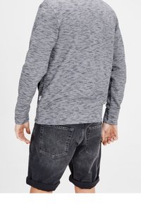Grå, texturerad sweatshirt med rund hals, i kombination med mörkgrå shorts med uppvikta ben och två bakfickor.