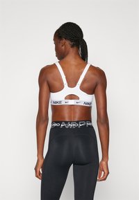 Hvit sportbh med justerbare stropper og utskjært bakstykke, med en svart logo-stripe. Svart leggings med merket midjebånd.