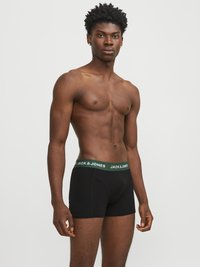 Boxer neri con elastico verde che presenta il nome del marchio "JACK & JONES" in bianco. Tessuto liscio; design aderente.