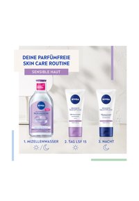 Eine transparente Flasche mit Mizellenwasser, zwei weiße Tuben mit Tages- und Nachtcreme, die lila Akzente aufweisen. Textetiketten zeigen die Schritte der Routine an.