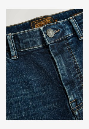 Dunkelblaue Jeans aus Denim mit einem Knopfverschluss, kupferfarbener Naht und einem Etikett mit der Aufschrift "NEXT Premium Denim Goods" in der Nähe des Bundes.