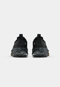 Pair of black athletic shoes shown from the back, featuring thick soles with rugged tread and pull tabs on the heels.