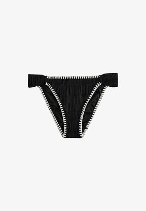 Fekete texturált bikini alsó, széles oldalszíjakkal és fehér cikk-cakk varrással a széleken, fehér háttér előtt.