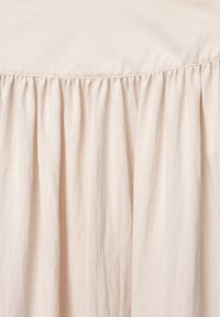 Light beige, textured fabric with gathered ruffles at the top, flowing downward in soft pleats. Smooth, lightweight material.