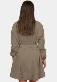 Abito a maniche lunghe, morbido e ampio, in un tessuto marrone chiaro texture, con vita con cintura e silhouette a gonna a campana.