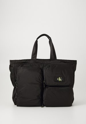 Grand sac fourre-tout noir en nylon avec deux poches avant, fermetures éclair, et accent de logo brodé. Dispose de poignées robustes pour un transport facile.