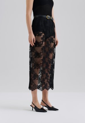 Svart blonde lang skjørt med blomsterdesign, gjennomsiktig stoff, scalloped kant. Kombinert med en svart tank topp og et bredt skinnbelte.