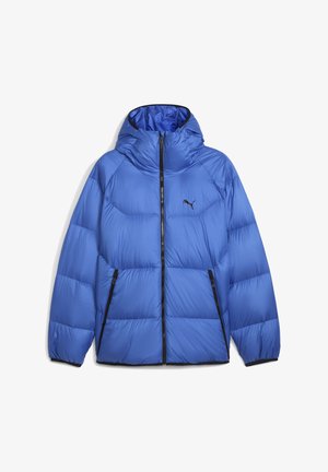 Veste matelassée bleue avec capuche, présentant un design matelassé, des accents noirs, une fermeture éclair avant et deux poches latérales zippées.