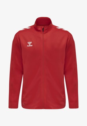 Czerwona polarowa kurtka z wysokim kołnierzem i pełnym zamkiem. Posiada białe akcenty w kształcie chevronu na ramionach oraz małe logo na piersi.